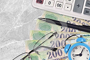 200 Hungarian forint bills and calculator with glasses and pen. Business loan or tax payment season concept. Time to pay taxes