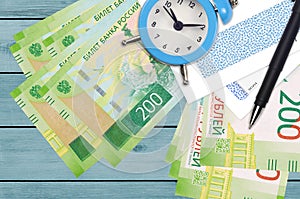 200 russian rubles bills and alarm clock with pen and envelopes. Tax season concept, payment deadline for credit or loan.