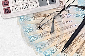 200 Ukrainian hryvnias bills fan and calculator with glasses and pen. Business loan or tax payment season concept