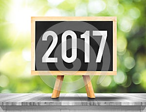 2017 new year on blackboard on plank white wood with green abstract blur tree background,Ecology Business concept