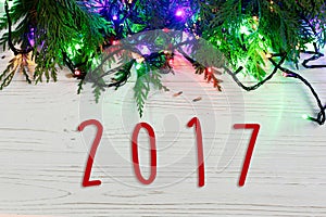 2017 sign text on christmas frame of garland lights on fir branches. stylish border on white rustic wooden background. space for