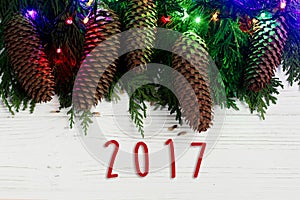 2017 sign text on christmas garland lights and pine cones on fir