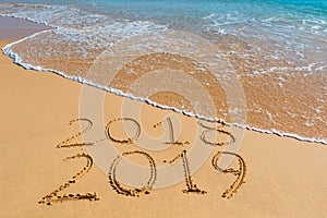 2018 2019 inscription written in the wet yellow beach sand being