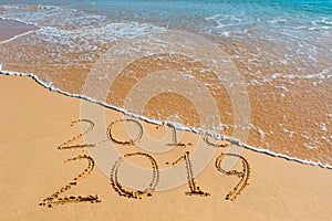 2018 2019 inscription written in the wet yellow beach sand being