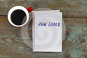 2018 goals list with notebook, cup of coffee on wooden desk. To