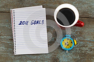 2018 goals list with notebook, cup of coffee on wooden desk. To