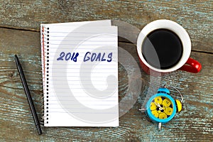 2018 goals list with notebook, cup of coffee on wooden desk. To