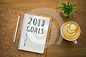 2018 Goals on white notepad with coffee latte on wood table