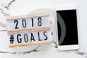 2018 goals on wood box and smart phone with blank on screen at o