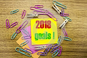 2018 goals on yellow sticky note, on wooden background. New Year resolutions concept.