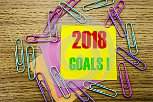 2018 goals on yellow sticky note, on wooden background. New Year resolutions concept.