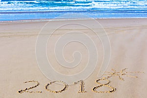 2018 inscription on wet beach sand and sea waves on background