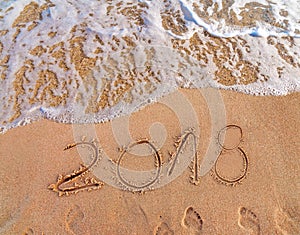 2018 written on sandy beach New Year is coming like date holiday