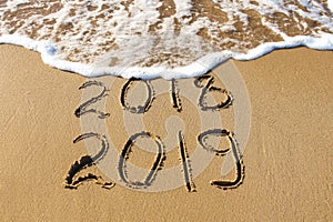 2019, 2018 years written on sandy beach sea. Wave washes awa