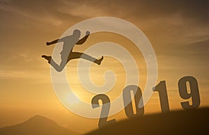 2019 brave man successful concept,silhouette man jumping over the sun between gap of the mountain to 2019 new year, feel like a wi