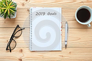 2019 Goals with notebook, black coffee cup, pen and glasses on table, Top view and copy space. New Year New Start, Resolution, Sol