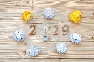 2019 Happy New years with lightbulb with crumbled paper and wooden number on table. New Start, Idea, Creative, Innovation, Resolut