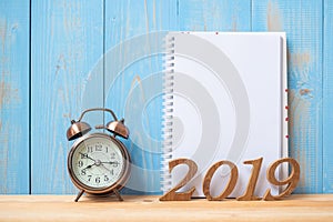 2019 Happy New years with notebook, retro alarm clock and wooden number on table and copy space.