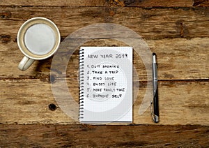 2019 New Year Resolutions written on notebook with pen and coffee on wood table in Happy life goals