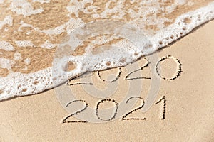 2020 2019 inscription written in the wet yellow beach sand being washed with sea water wave