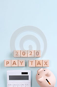 2020 goal, finance plan abstract design concept, wood blocks on blue table background with piggy bank and calculator, top view,