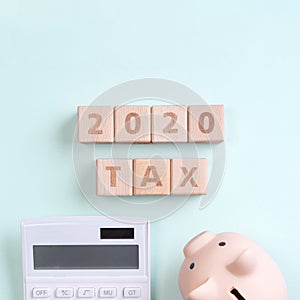 2020 goal, finance plan abstract design concept, wood blocks on green table background with piggy bank and calculator, top view,