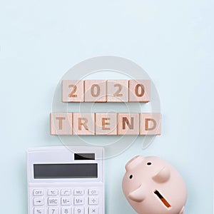 2020 goal, finance plan abstract design concept, wood blocks on green table background with piggy bank and calculator, top view,