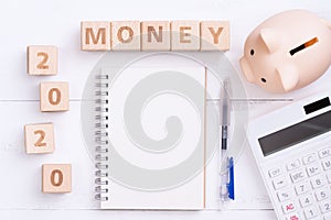2020 goal, finance plan abstract design concept, wood blocks on white table background with piggy bank and calculator, top view,