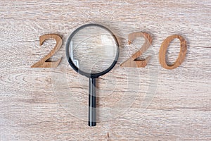 2020 Happy New year with Businessman holding glass magnifying and wooden number on table. New Start, Vision, Resolution, Strategy
