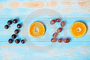 2020 Happy New Year and New You with fruits, Black grapes, Orange, Red grapes on blue wood background. Goals, Healthy, Healthcare