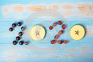 2020 Happy New Year and New You with fruits, Black grapes, Red grapes and green apples on blue wood background. Goals, Healthy,