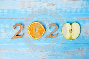 2020 Happy New Year and New You with green apple and Orange fruits on blue wood background. Goals, Healthy, Healthcare, Resolution