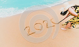 2020 New Year. 2020 woman written on sandy beach with wave foam at sea beach. Happy New Year. Tropical celebration.New Years