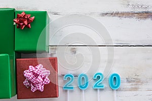 2020 New Year Concept. Top view of number light blue candle on old and cracked wooden plank and red and green gift boxes with copy