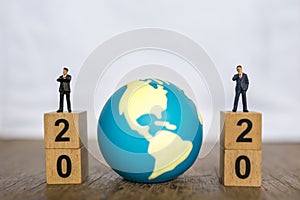 2020 New year , Global and Business concept. Close up two businessman miniature figure people standing on top of stack of wooden