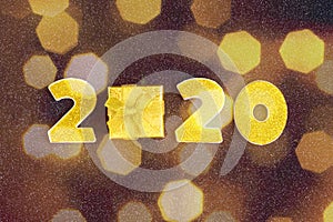 2020 numbers decorated with gold sequins,  ribbon, ball on shiny black background.