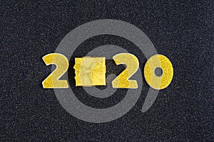 2020 numbers decorated with gold sequins,  ribbon, ball on shiny black background.