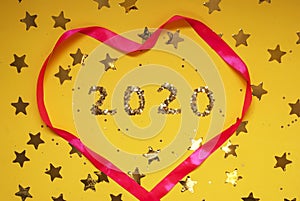 2020 numbers from small confetti with shining stars and a pink heart. Festive background. New Year. Top view.