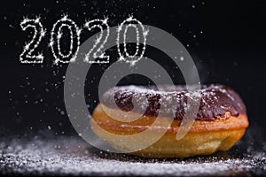 2020 sparkling text next to donut powdered with sugar