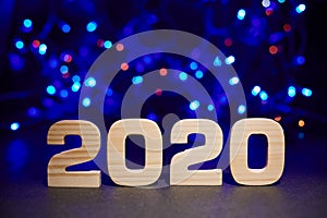 2020 wooden letters on a background of blue bokeh lights. Christmas or New Year card