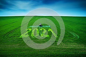 2021 Happy New Year concept and Aerial view of farming tractor plowing and spraying on field