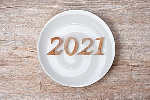 2021 Happy New Year and New You with white plate on wood background. Goals, Healthy, Healthcare, Resolution, Time to New Start,