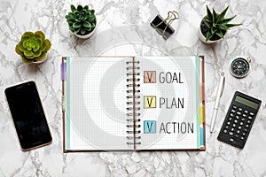 2021 new year goal,plan,action text on open notepad, glasses, cup of coffee, pen, smartphone, succulents on marble table Top view