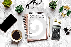 2021 new year goal,plan,action text on open notepad, glasses, cup of coffee, pen, smartphone, succulents on marble table Top view
