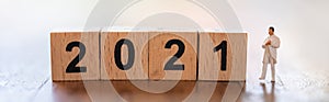 2021 New Year, Healthcare Cover Page concept. Closeup of docter miniature figure people standing with wooden number block on