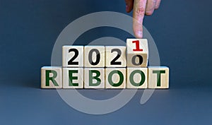 2021 reboot new year symbol. Male hand flips wooden cube and change the inscription `Reboot 2020` to `Reboot 2021`. Beautiful