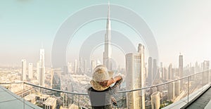 2022: Burj Khalifa View from sky view downtown, lady by infinity pool looking at the tallest building