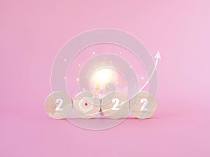 2022 business growth target. lightbulb, target icon, a graph on pink background. Space for your text.