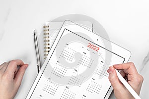 2022 calendar closeup, tablet computer screen. White marble background. Concept of planning appointment and meeting