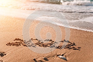 2022 figures on sandy beach Happy New Year 2022, number hand written in the golden sand on beautiful sunset golden light